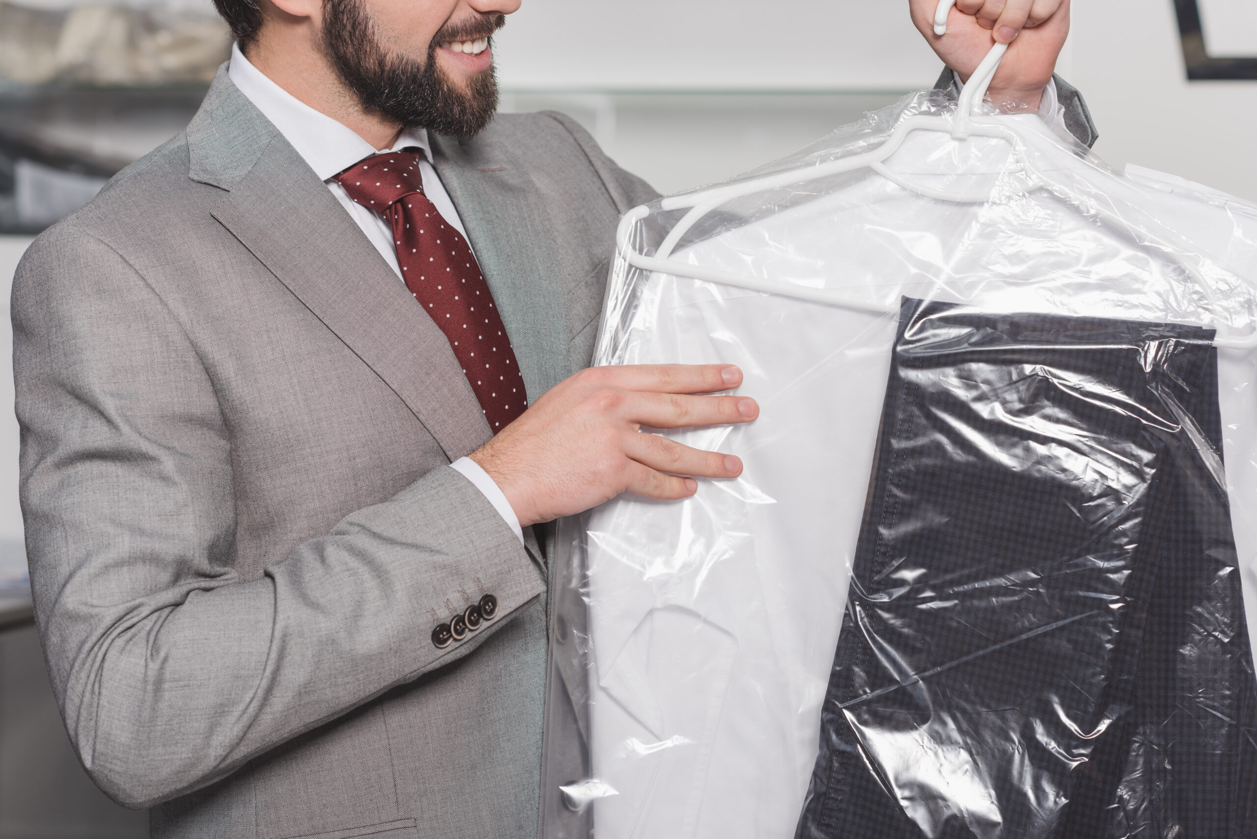 A man is putting a shirt in a plastic bag.